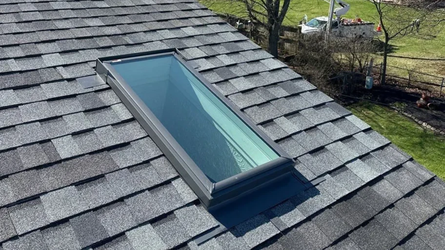 Close-up of a new, rectangular skylight installed on a gray shingle roof